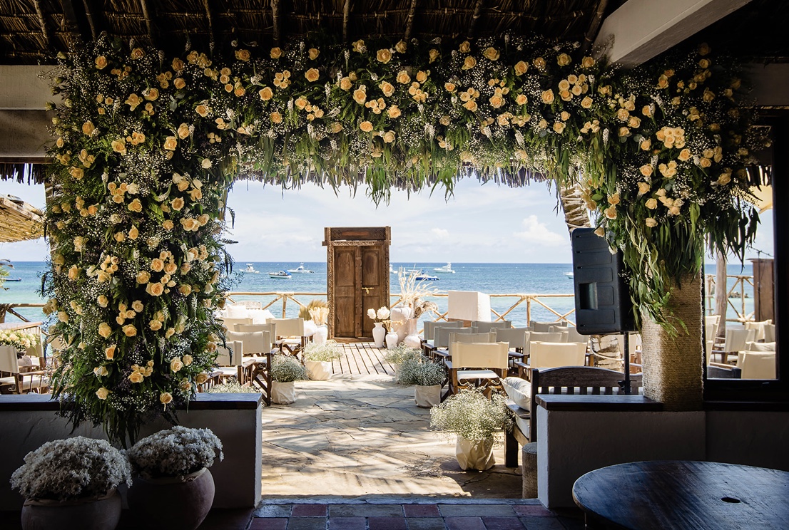 Yellow rose and foliage installation framing a seaside event terrace