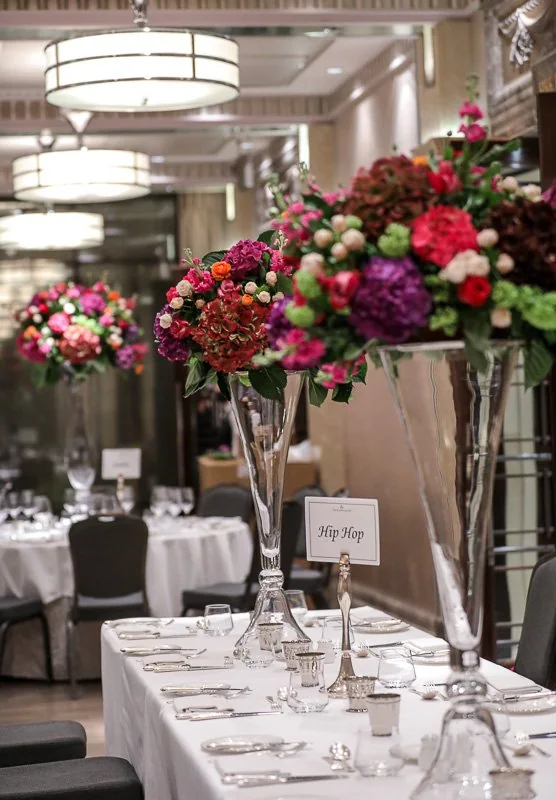 Tall pink event flowers beside formally laid tables