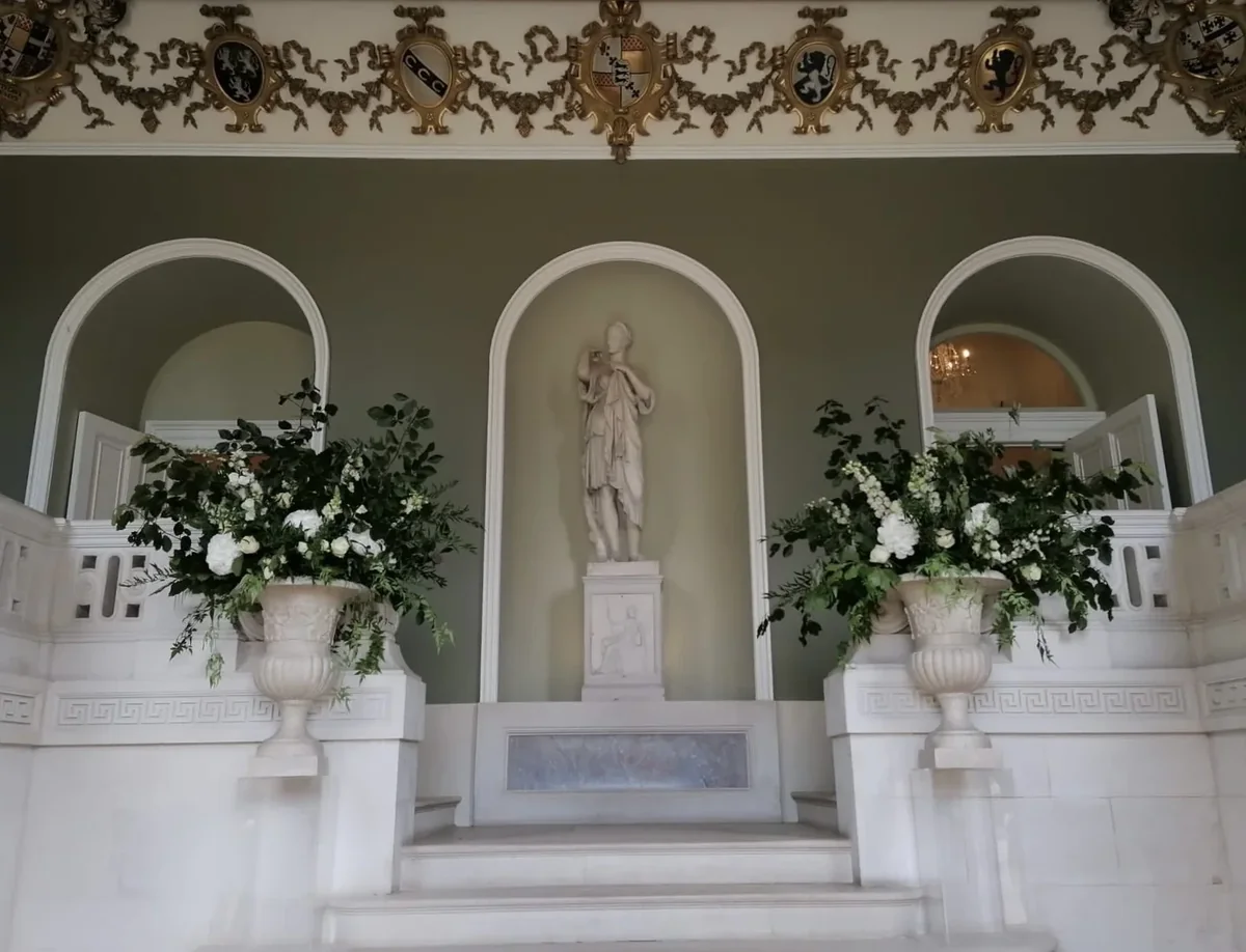 White and green urn arrangements flanking a ceremony backdrop