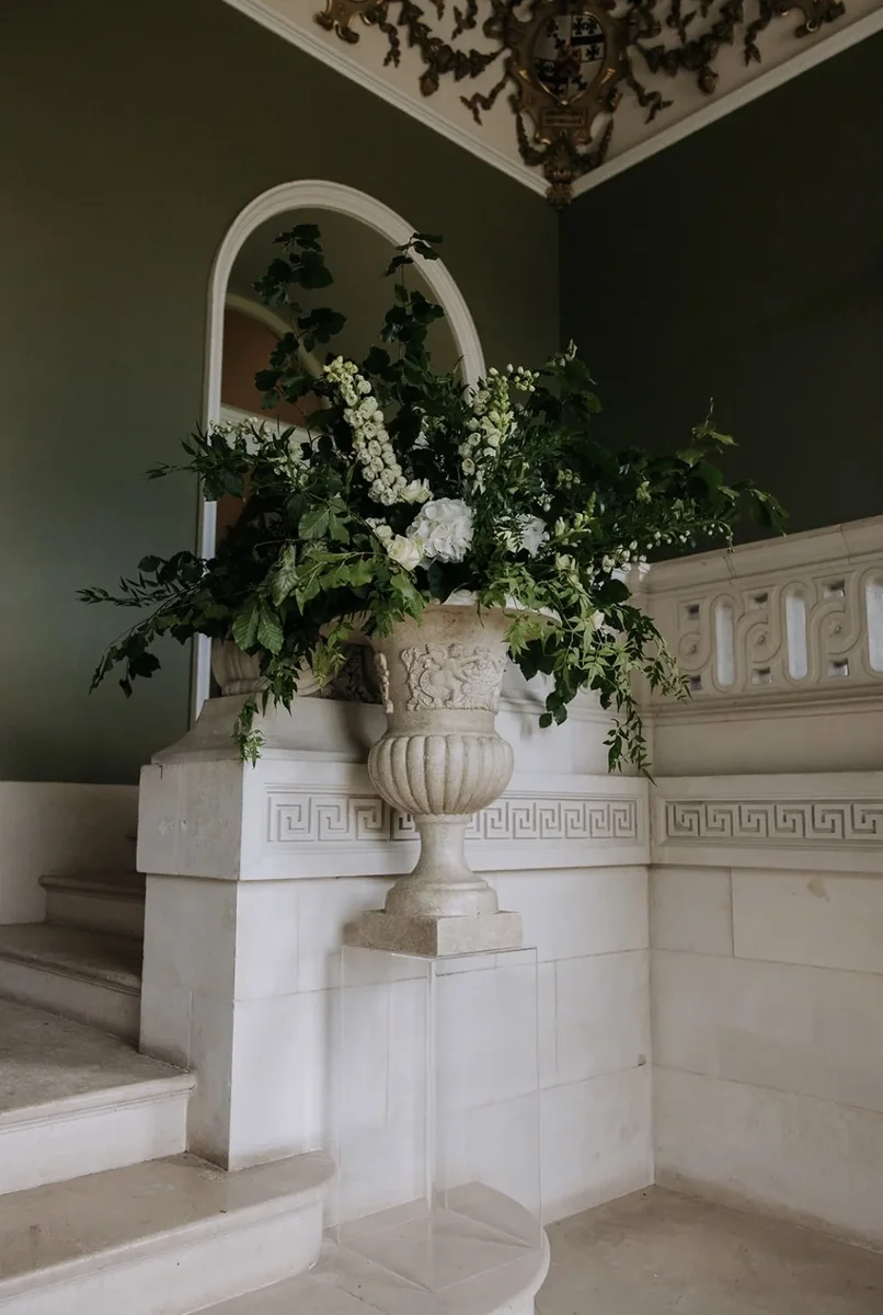 White and green urn arrangement on an indoor balustrade