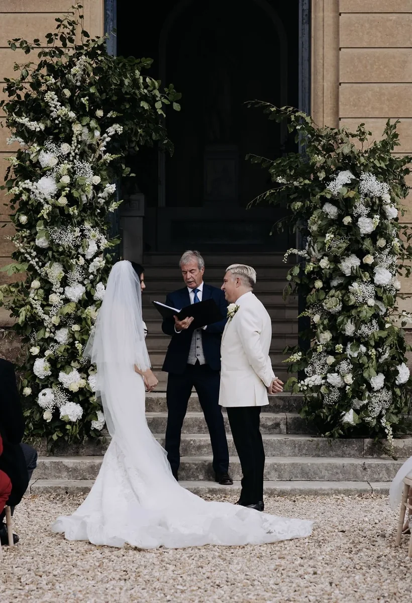 Outdoor wedding ceremony framed by abundant white flowers