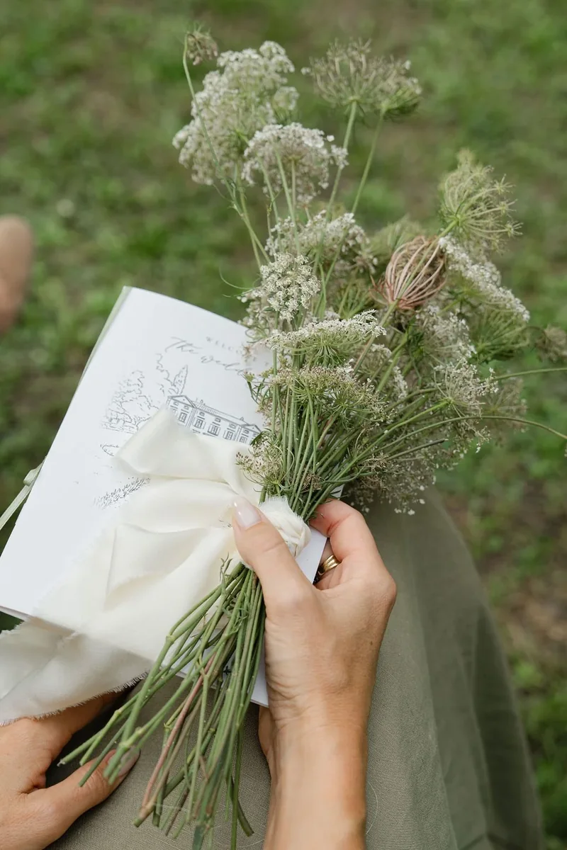 Bride holding a delicate dried flower posy and wedding stationery