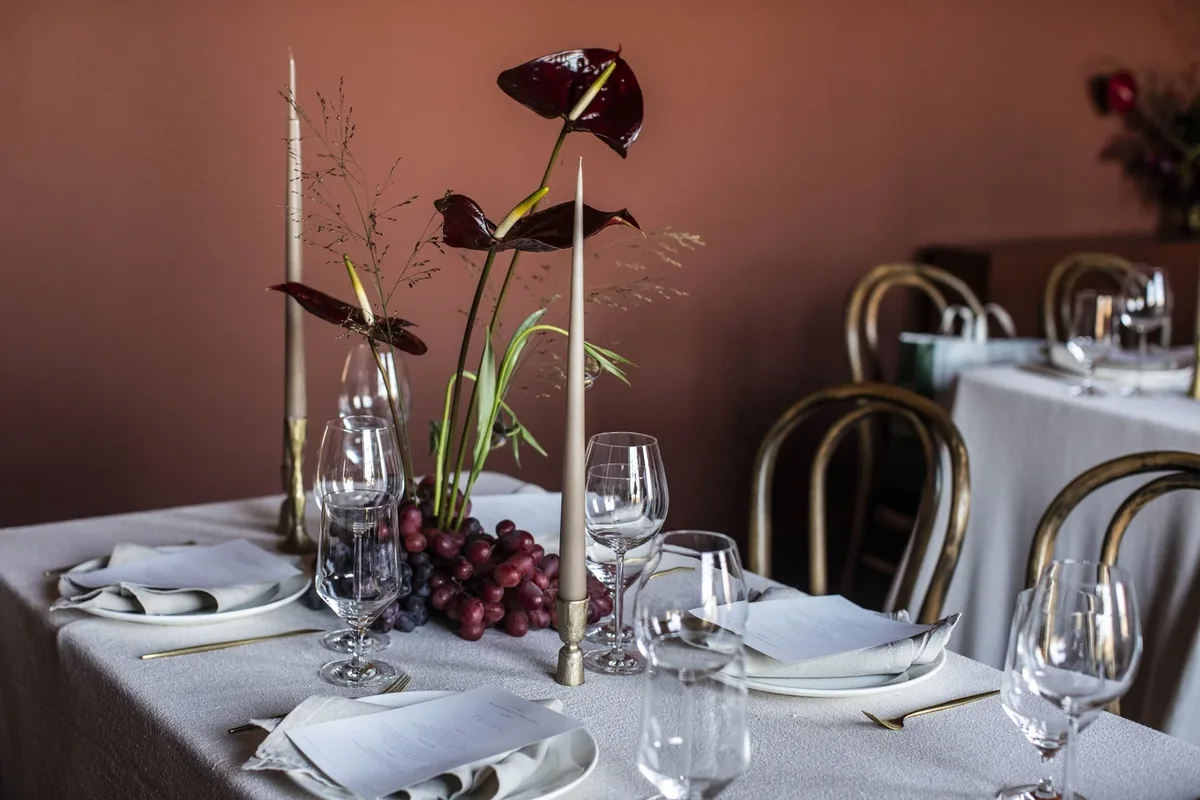 Private dining table with sculptural flowers, grapes and taper candles