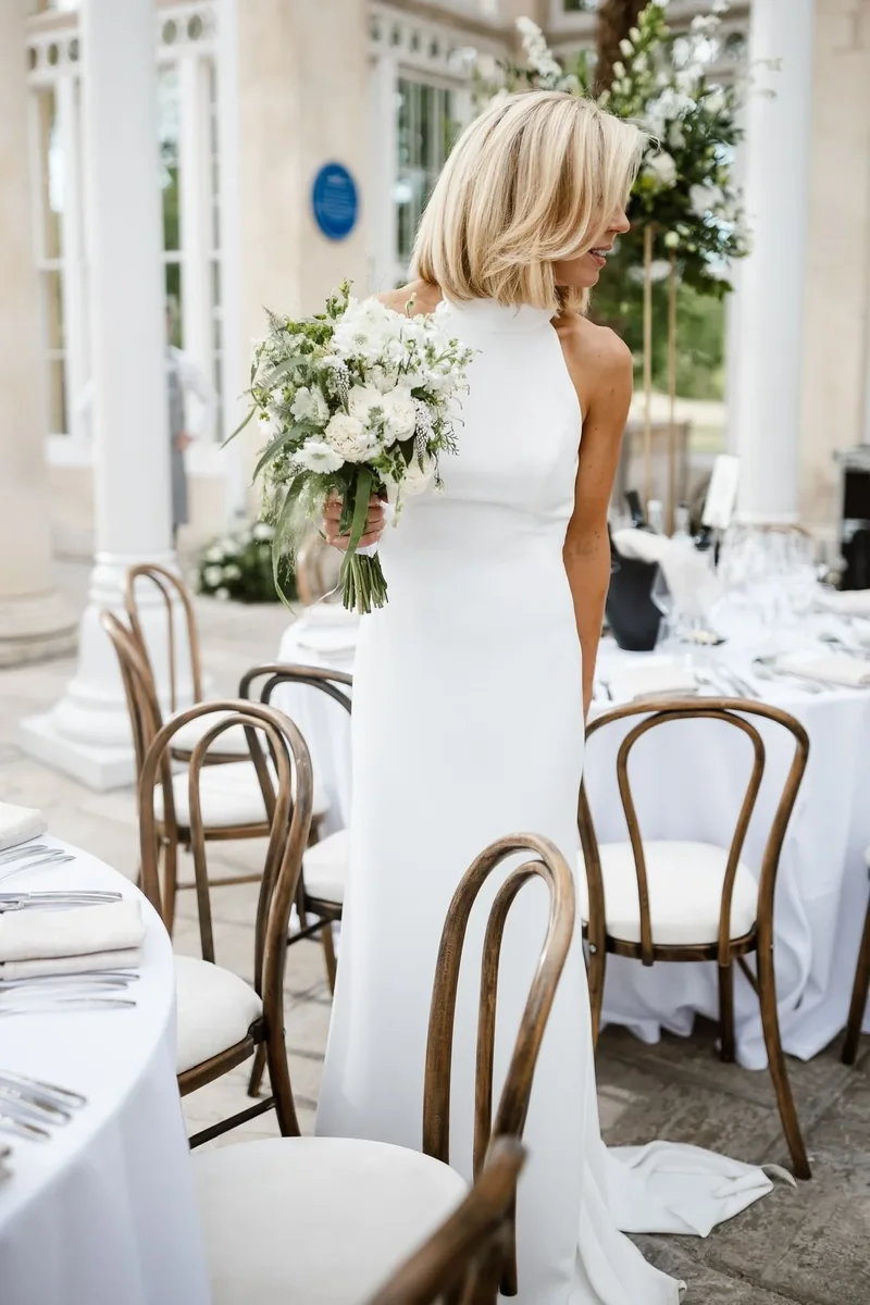 Bride carrying a white bouquet through the wedding reception