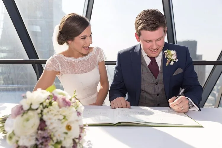 Newlyweds signing the wedding register with flowers beside them