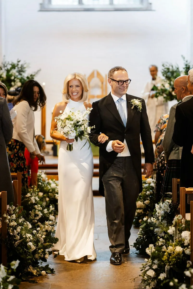 Bride walking down a flower-lined church aisle