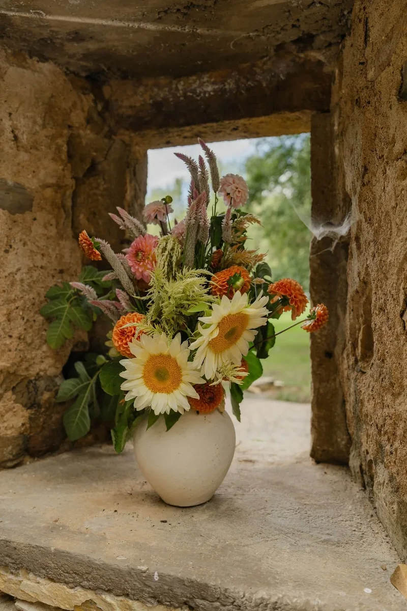 Seasonal flowers arranged in a stone window at a country wedding