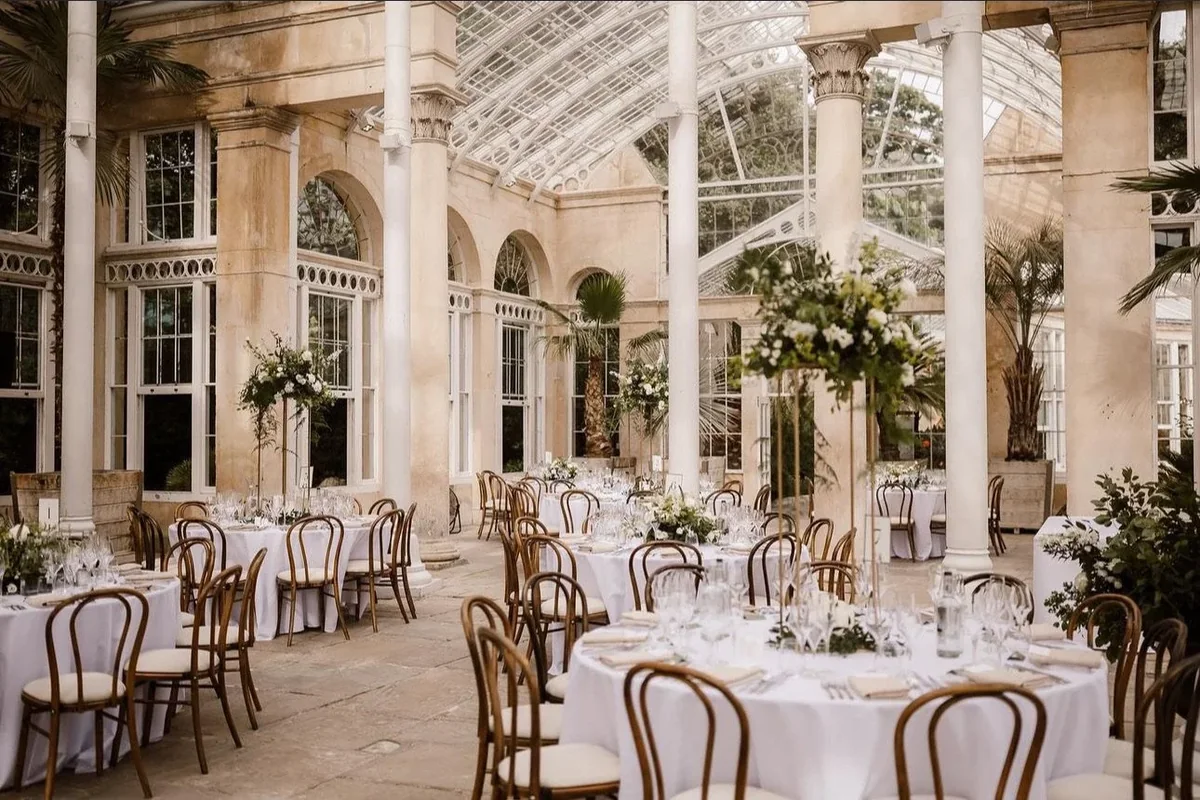 Glasshouse wedding reception with white and green flowers