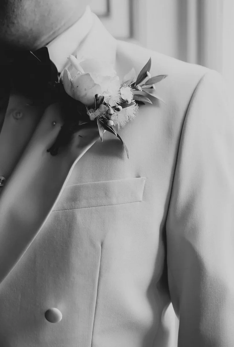 Monochrome detail of a floral buttonhole on a wedding suit