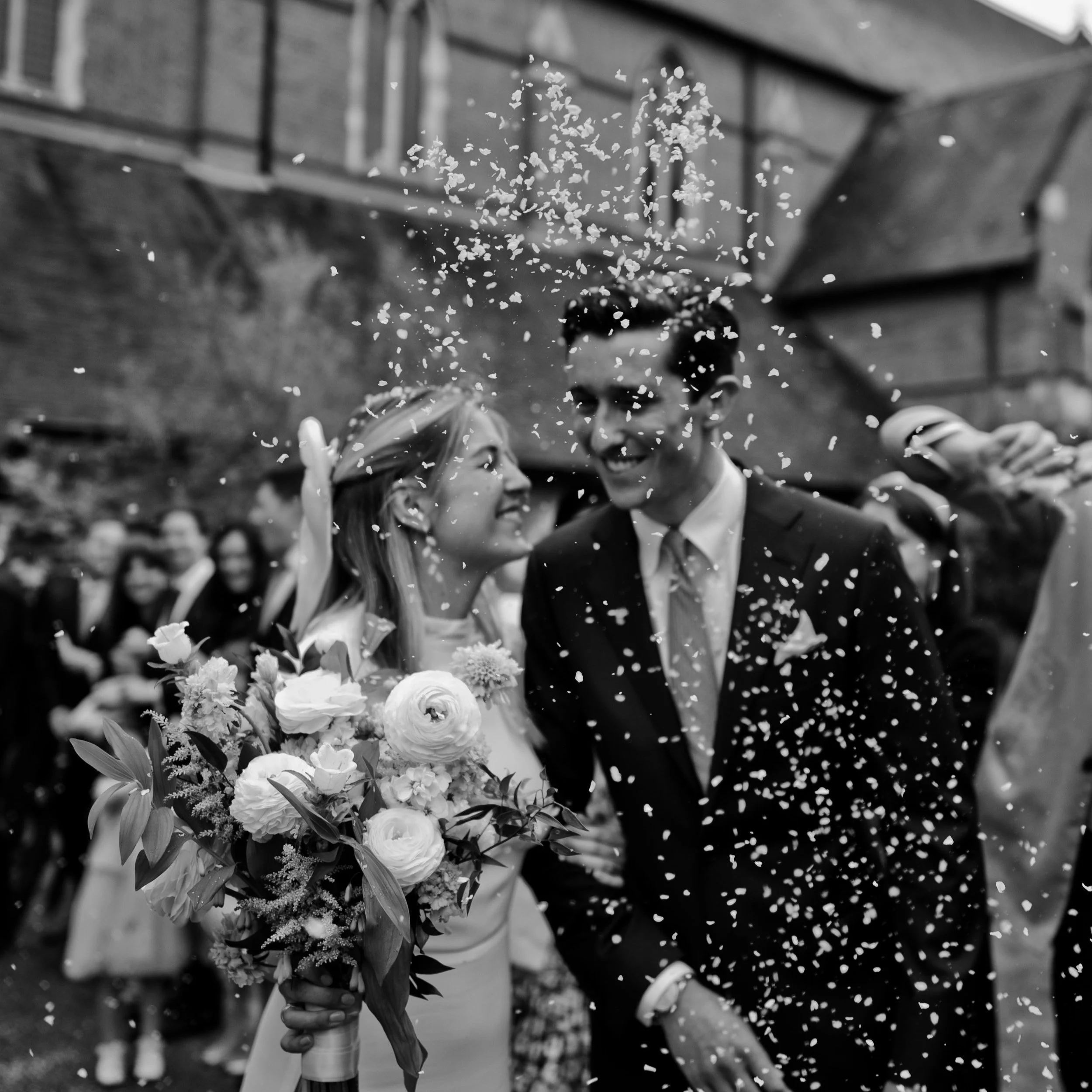Newly married couple walking through falling confetti