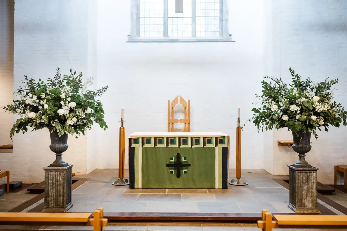 Church altar framed by white and green ceremony flowers