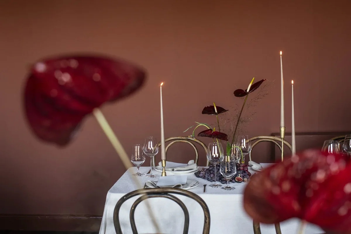 Deep red calla lilies and taper candles on a private dining table