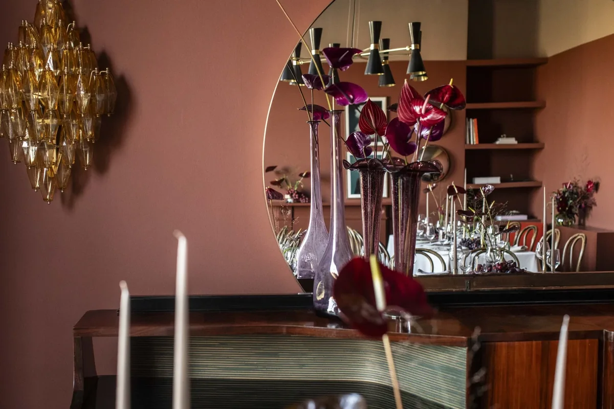 Sculptural calla lily arrangement reflected in a dining-room mirror