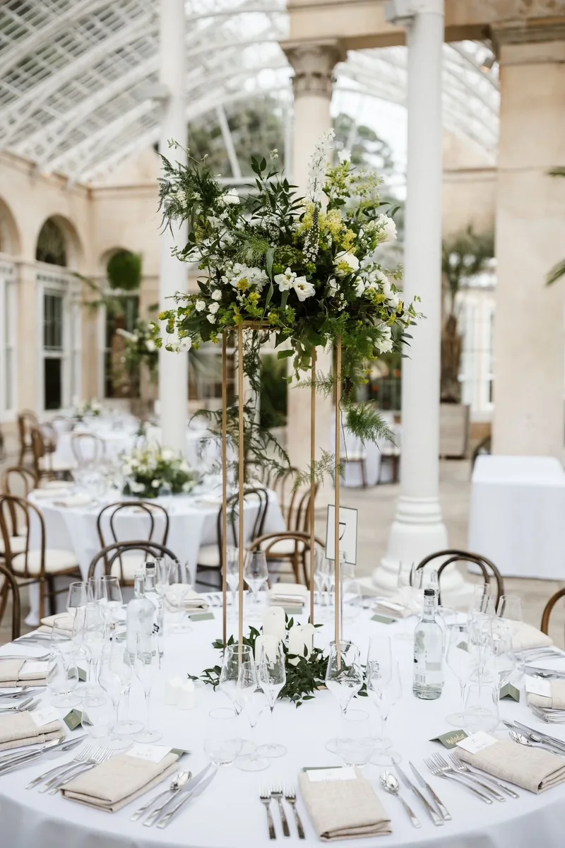 White and green wedding table centrepiece in a glasshouse