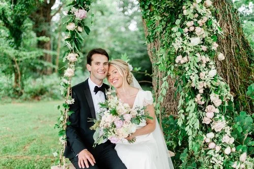 Newlyweds beneath a flower-covered woodland arch
