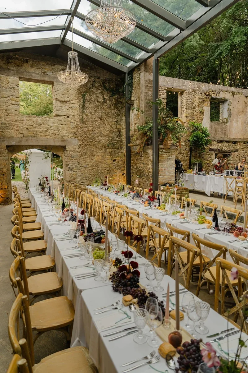 Long wedding breakfast table dressed with seasonal flowers in a stone barn