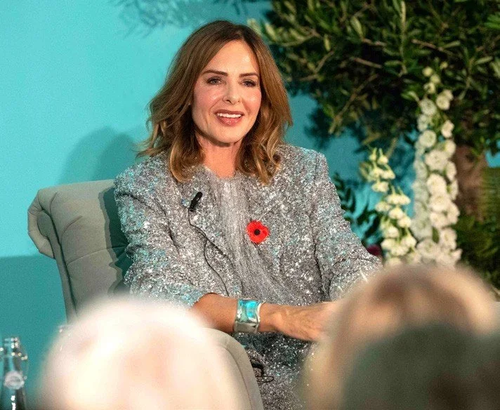 Speaker at a brand event framed by white flowers and greenery