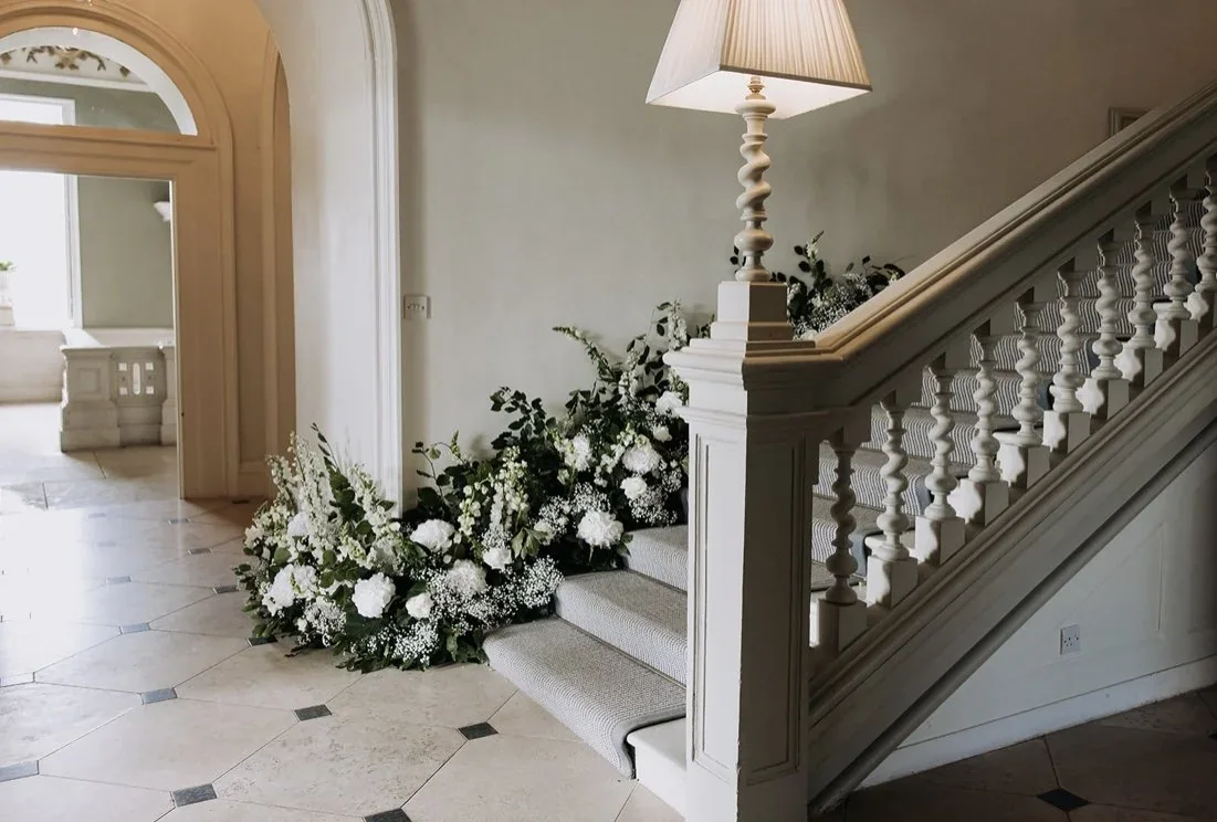 White wedding flowers arranged along a country house staircase