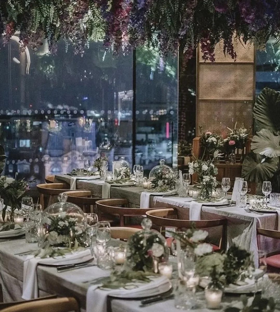 Evening event tables arranged beneath hanging flowers