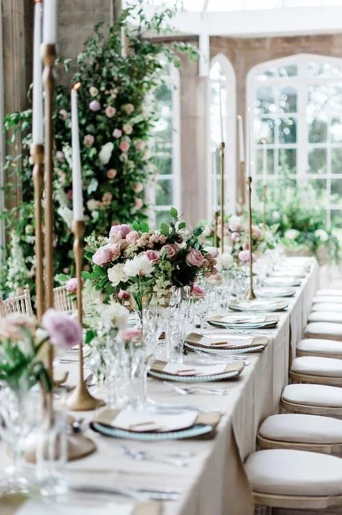 Long reception table dressed with soft pink flowers